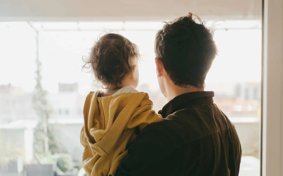 Backs of father and child looking out a window at Te Pā Tāhuna Queenstown New Zealand