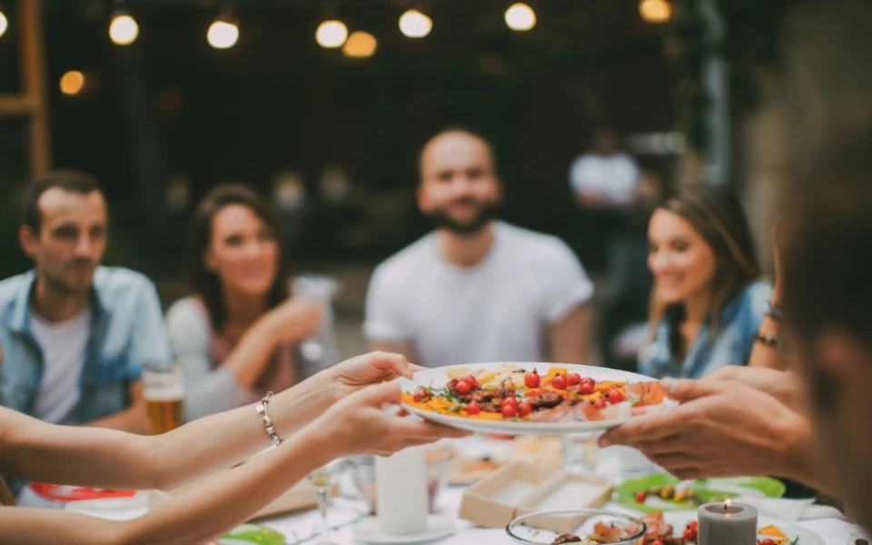 Friends around a dining table sharing food and talking